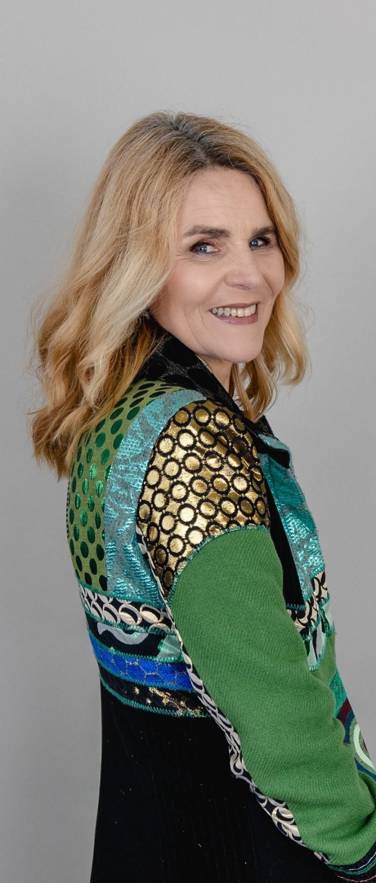 Selbstportrait Frau mit blonden Haaren, trägt ein buntes, intricately gestaltetes Kleid.
